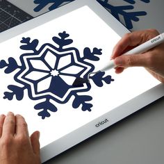 two hands are using a marker to draw a snowflake design on a piece of paper