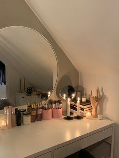 a vanity with candles, mirror and other items on it in a room that looks like an attic