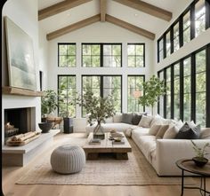 a living room filled with lots of furniture and large windows in the wall behind it