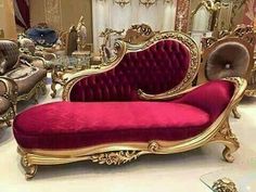 a red couch sitting in front of a mirror on top of a white floor covered in furniture