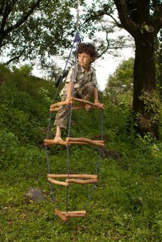 a young boy on a wooden ladder in the woods