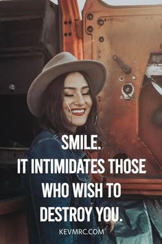 a woman wearing a cowboy hat sitting in front of an old truck with the words smile it intimates those who wish to destroy you