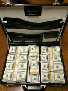 a briefcase filled with money sitting on top of a wooden floor