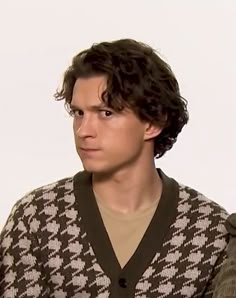 a young man with curly hair wearing a sweater