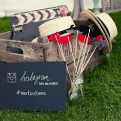 an old wooden crate filled with hats and other items sitting on the grass next to a sign