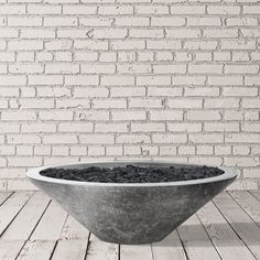 a concrete bowl on a wooden floor in front of a brick wall and white bricks