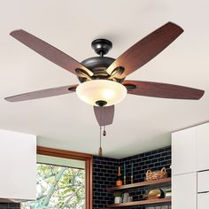 a ceiling fan that is hanging from the ceiling in a room with white cabinets and black brick walls