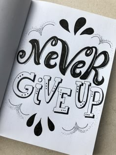 an open notebook with the words never give up written in black ink on top of it