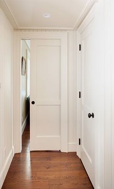 an empty hallway with white walls and wood flooring is seen in this image from the front door