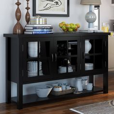 a black buffet table with plates and bowls on it next to a wall mounted painting