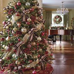 a decorated christmas tree in the middle of a room with piano and chandelier