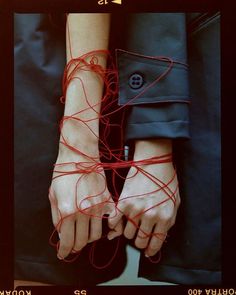 a woman's hands with red string attached to them