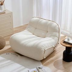 a white bean bag chair sitting on top of a wooden floor next to a table