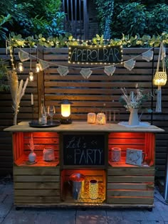 an outdoor party with lights and decorations on the outside wall, including a bar cart