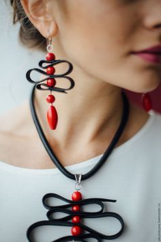 a woman wearing a black and red necklace with an intricate design on the back of it