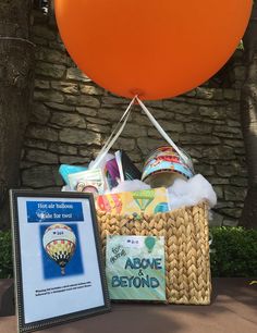 an orange balloon is in the air next to a basket with books and other items