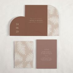 the wedding stationery is made up of brown and white paper with palm leaves on it