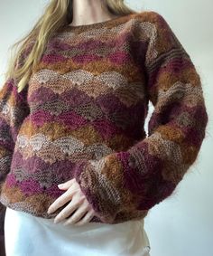 a woman is wearing a sweater made out of multicolored knits and has her hands on her hips