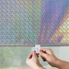 a person is painting the window with metallic foil on it's roller shade that looks like a flower of life pattern