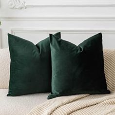 two dark green pillows sitting on top of a couch