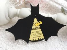 a bat shaped ornament hanging from a white curtain rod with black and yellow lettering on it