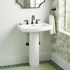 a white sink sitting under a bathroom mirror next to a wall mounted faucet