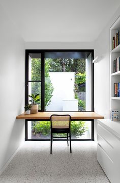 an empty room with a desk, chair and bookshelf in front of the window