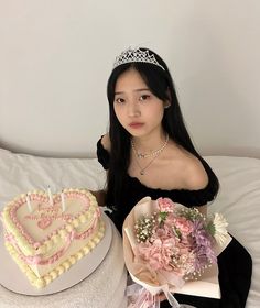 a woman in a tiara sitting next to two heart shaped cakes with flowers on them