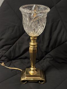 an old fashioned glass candle holder on a black tablecloth with a gold colored base