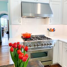 red tulips are in a vase on the kitchen counter next to an oven