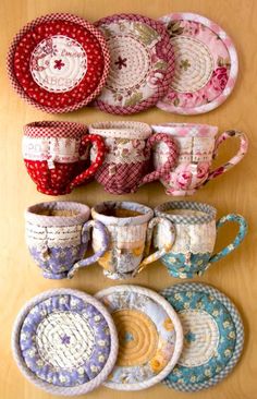 several cups and saucers are lined up on a wooden table with doily covering them