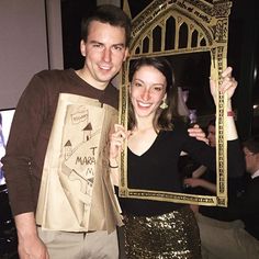 a man and woman posing for a photo with paper bags in front of them