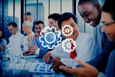 group of people sitting around a table working on laptops with gears coming out of them