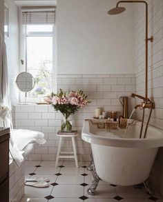 a white bathroom with black and white tile flooring, an antique claw foot bathtub