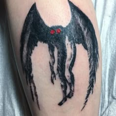 a bat tattoo on the arm with red eyes