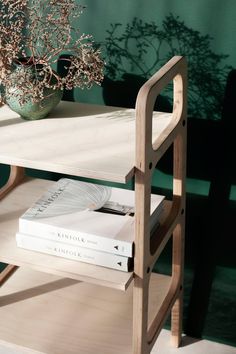 a table that has some books on it and a vase with flowers in the background