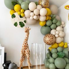 a giraffe standing in front of a bunch of balloons on the side of a wall