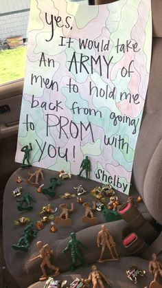 a car seat filled with toys and a sign that reads yes, it would take an army of men to hold me back from going to prom with you