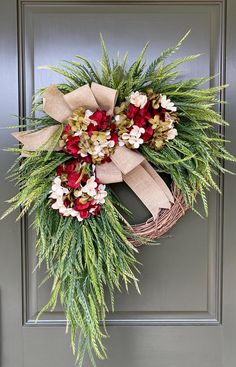 a wreath with red and white flowers is hanging on the front door