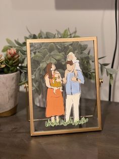 an image of a family in a frame on a table next to a potted plant