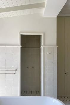 a white bath tub sitting next to two tall cabinets