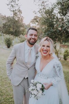 a bride and groom pose for a photo in their wedding day attire, smiling at the camera