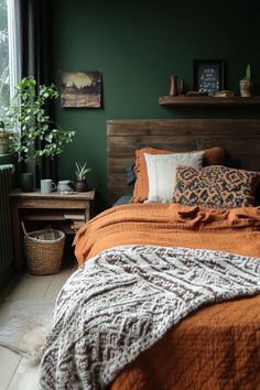 a bedroom with green walls and orange bedding, plants on the nightstands and a wooden headboard