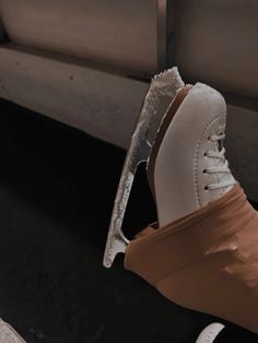 a pair of white shoes sitting on top of a floor next to a metal object