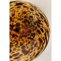 a brown and black glass bowl sitting on top of a white table next to a wall