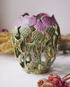 a decorative vase sitting on top of a table next to dried flowers