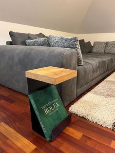 a living room with a gray couch and wooden table in front of it on hard wood flooring