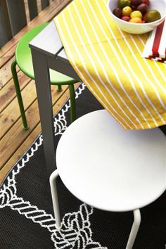 a bowl of fruit sitting on top of a table next to two green and white chairs