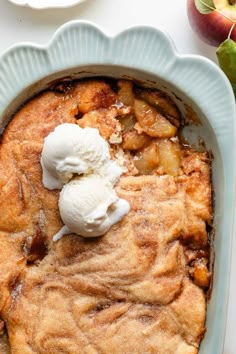 an apple cobbler with ice cream on top in a blue dish next to apples