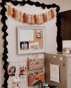 a bulletin board with pictures hanging on the wall next to a filing cabinet and other office supplies